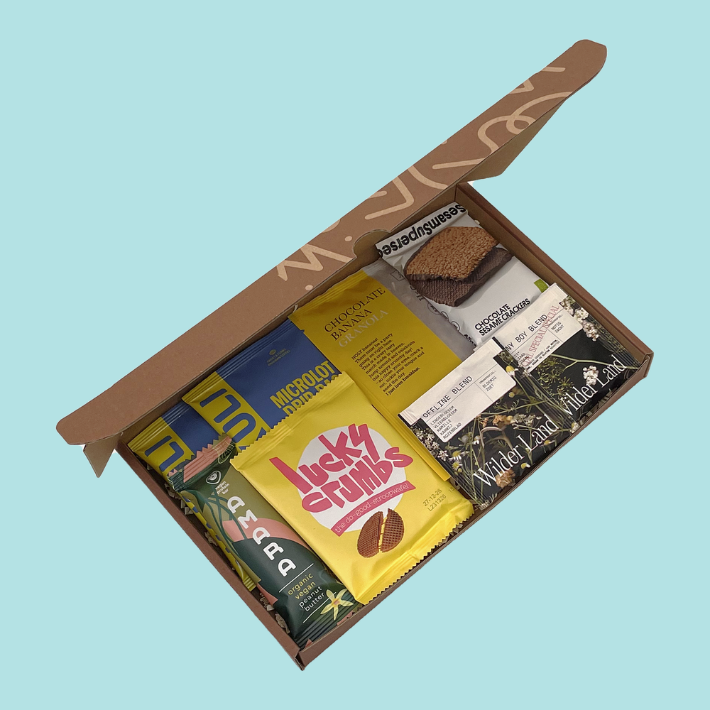 Active Box open from above with two Wakuli drip coffee bags, chocolate banana granola, a Lucky Crumbs stroopwafel, chocolate sesame crackers, an Amara bar and two Wilder Land teas