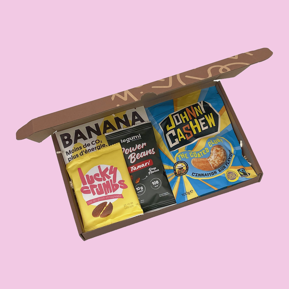 Nosh Box open from above with a 100g bag of Johnny Cashew, a Lucky Crumbs banana stroopwafel, Legumi roasted beans and Supersec dried fruit